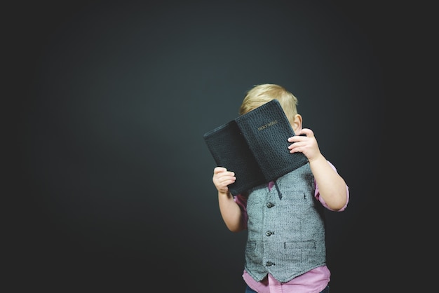 Hermosa foto de un niño sosteniendo una Biblia abierta