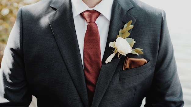 Hermosa foto del novio con una flor blanca en un traje