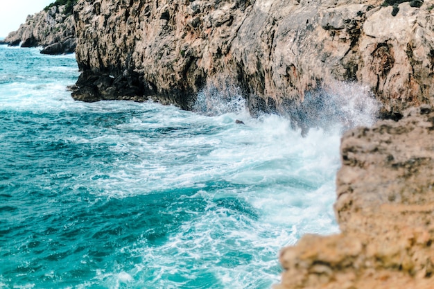 Foto gratuita hermosa foto de las olas del mar golpeando la costa rocosa, perfecta para el fondo