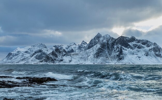 Una hermosa foto de las olas del mar con una montaña nevada de fondo