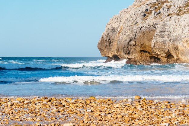 Hermosa foto de las olas del mar rompiendo en las rocas cerca de la playa