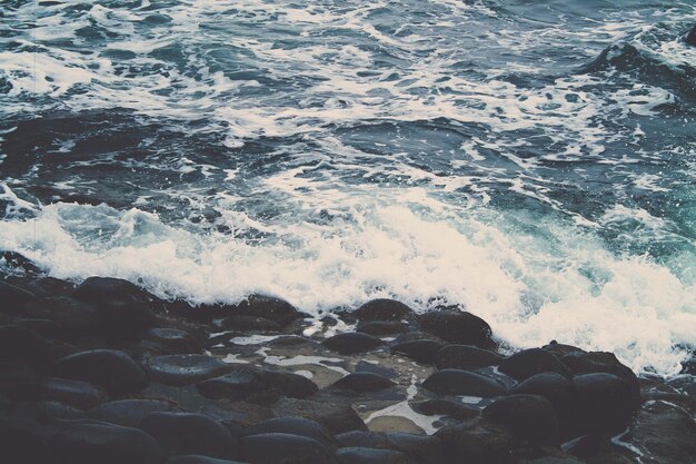 Hermosa foto de las olas del océano rompiendo sobre las piedras en la orilla