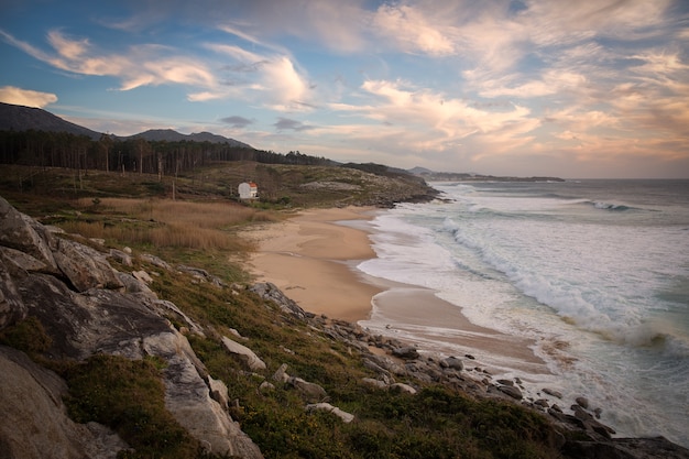 Hermosa foto de una orilla del mar con un paisaje de puesta de sol en un cielo azul nublado