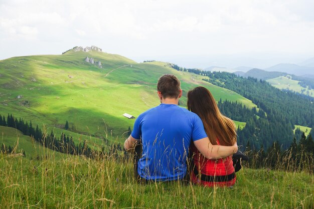 Hermosa foto de una pareja sentada en el campo de la montaña