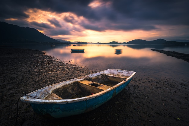 Hermosa foto de un pequeño lago con un bote de remos de madera en foco y nubes increíbles en el cielo