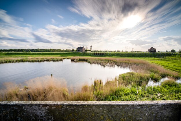 Hermosa foto de un pequeño lago rodeado de vegetación bajo un cielo nublado