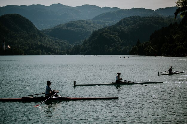 Hermosa foto de personas montando botes en el agua con montañas boscosas