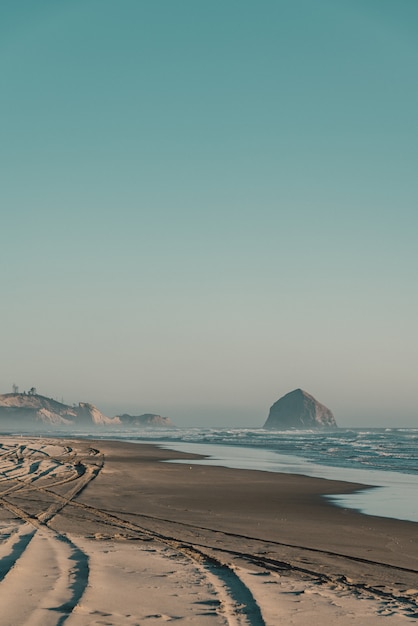 Hermosa foto de una playa de arena con olas increíbles en un día soleado