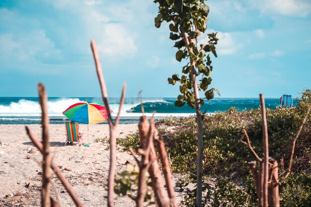 Hermosa foto de una playa con una sombrilla colorida y una silla de playa con olas increíbles