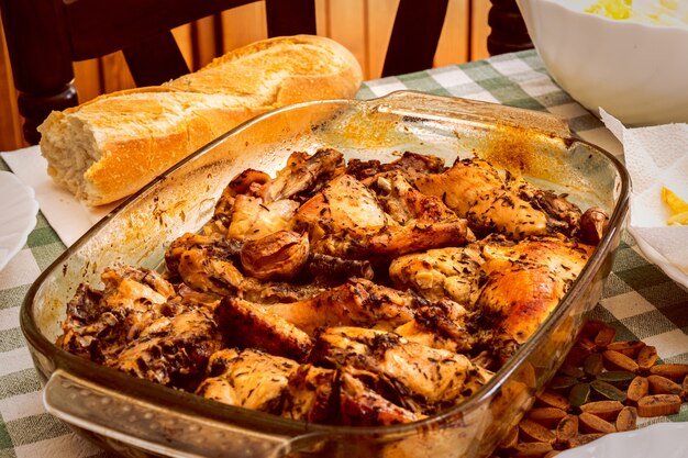 Hermosa foto de un pollo con salsa en la sartén y pan sobre la mesa