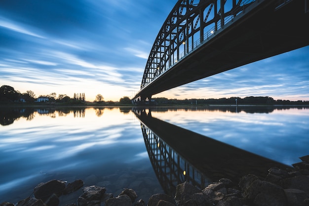 Hermosa foto de un puente sobre un lago reflectante durante la puesta de sol