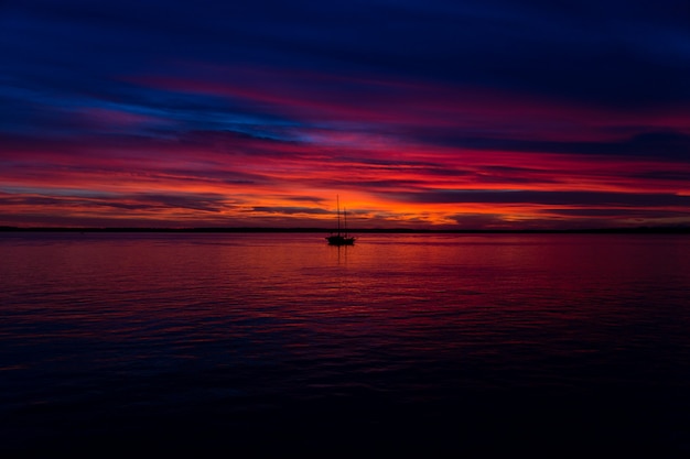 Hermosa foto de la puesta de sol en la playa con un barco en el medio