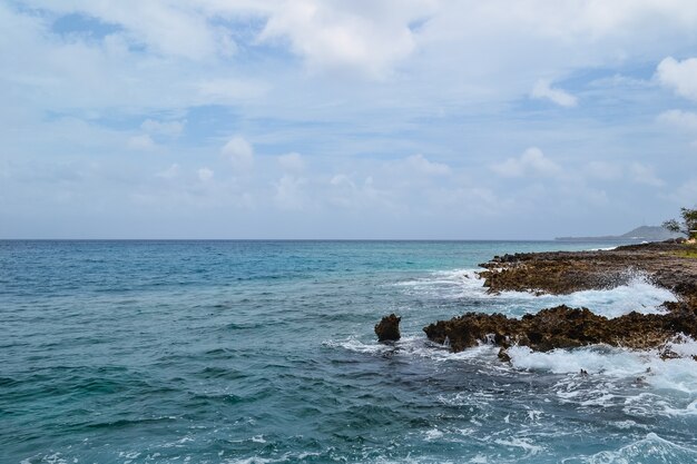 Hermosa foto de rocas en la orilla del mar con un cielo azul nublado