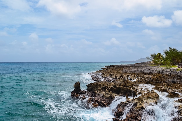 Hermosa foto de rocas en la orilla del mar con un nublado cielo azul de fondo