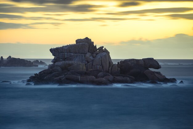 Hermosa foto de rocas en la orilla del mar durante la puesta de sol