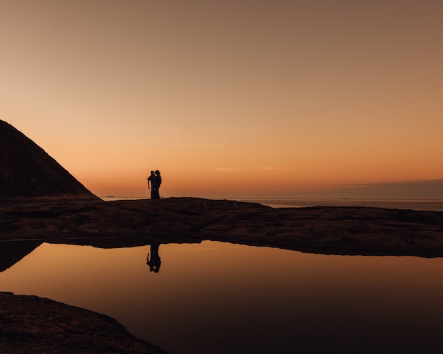 Hermosa foto de siluetas de personas en una playa durante el amanecer