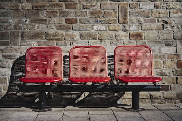 Hermosa foto de tres asientos rojos en la estación de autobuses de una zona urbana