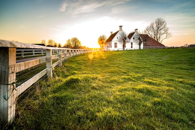 Hermosa foto de una valla que conduce a una casa en una zona de césped verde