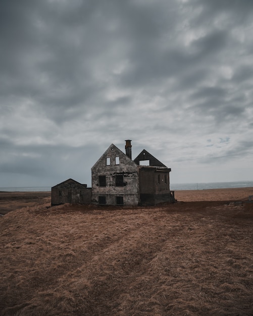 Hermosa foto de una vieja casa abandonada y medio destruida en un gran brownfield bajo cielo gris