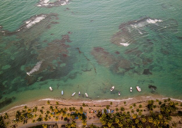 Hermosa fotografía cenital de la costa del mar con algunos pequeños botes estacionados cerca de la orilla