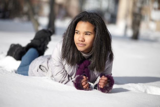 Hermosa hembra negra americana tumbado en la nieve al aire libre