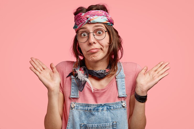 Foto gratuito la hermosa hippie tiene una expresión dudosa e indudable, extiende las palmas de las manos con vacilación, tiene un aspecto poco certero