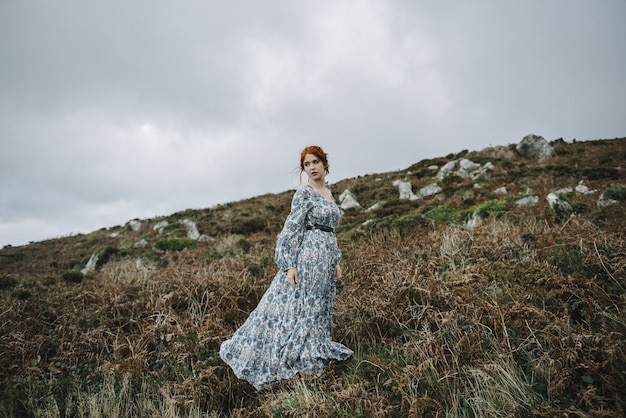 Hermosa imagen de una mujer pelirroja con una piel blanca pura en un atractivo vestido azul claro