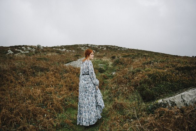 Hermosa imagen de una mujer pelirroja con una piel blanca pura en un atractivo vestido azul claro