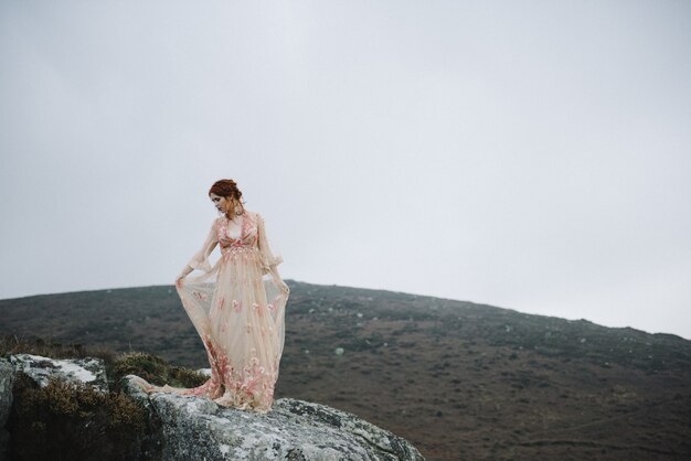 Hermosa imagen de una mujer pelirroja con una piel blanca pura en un atractivo vestido rosa claro