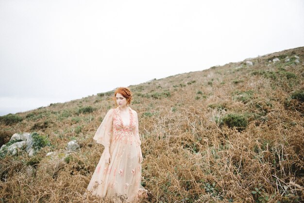 Hermosa imagen de una mujer pelirroja con una piel blanca pura en un atractivo vestido rosa claro