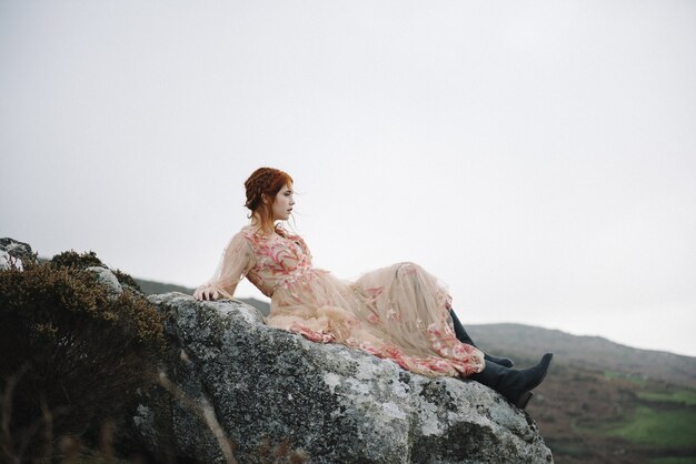 Hermosa imagen de una mujer pelirroja con una piel blanca pura en un atractivo vestido rosa claro