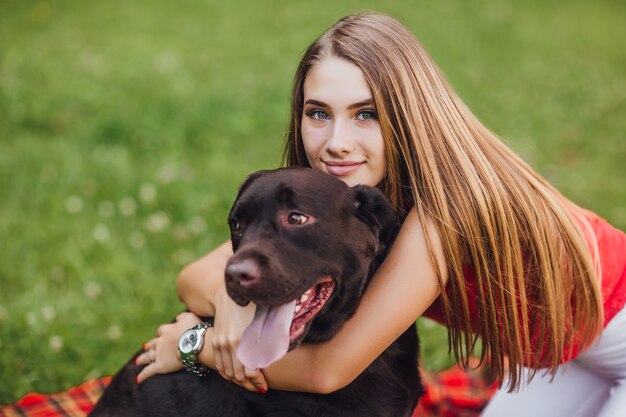 La hermosa joven abraza a su perro en el jardín