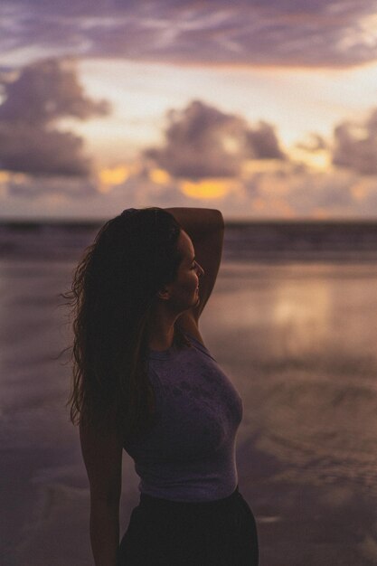 Hermosa joven al atardecer en el océano, Bali, Indonesia.