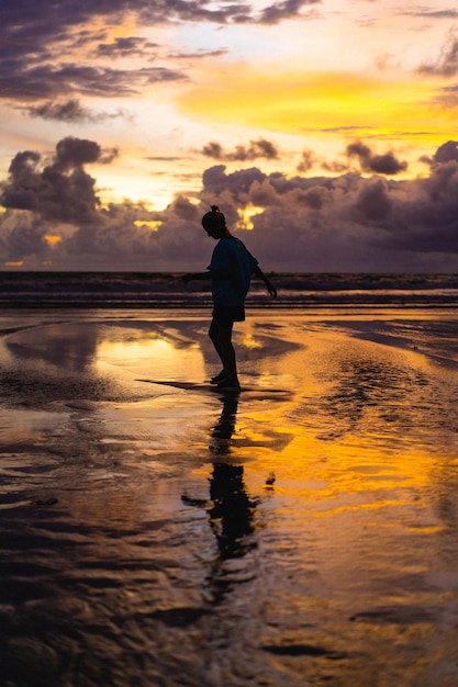 Hermosa joven al atardecer en el océano, Bali, Indonesia.