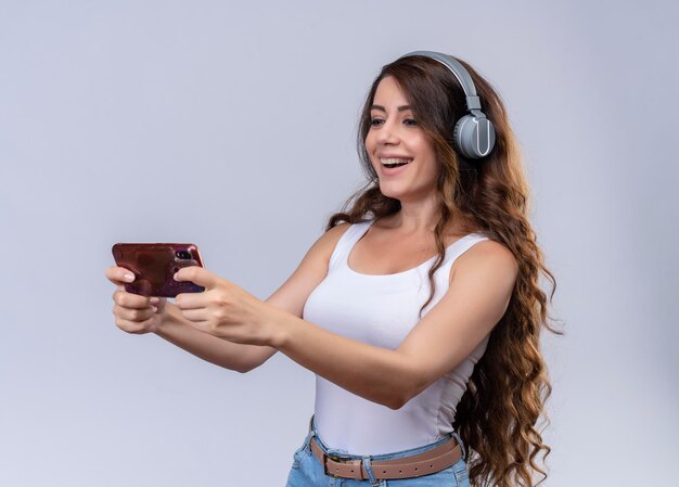 Hermosa joven alegre usando audífonos mediante teléfono móvil