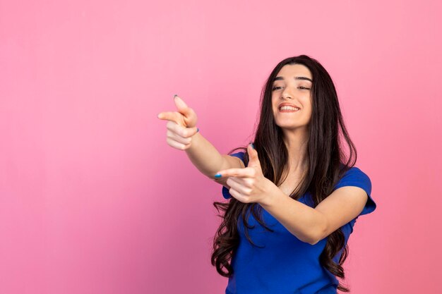 Hermosa joven arma de gesto con las manos y sonriendo Foto de alta calidad