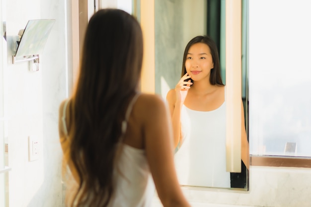 Hermosa joven asiática revisa su cara en el baño