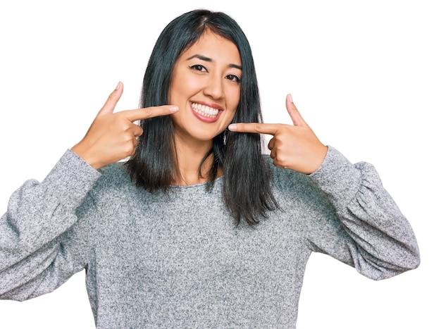 Hermosa joven asiática con ropa informal sonriendo alegre mostrando y señalando con los dedos los dientes y la boca. concepto de salud dental.