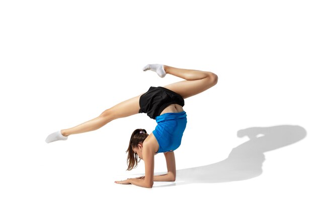 Hermosa joven atleta de estiramiento, entrenamiento en espacios en blanco, retrato con sombras