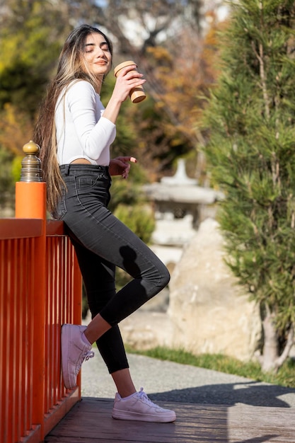 Hermosa joven se para y bebe café Foto de alta calidad