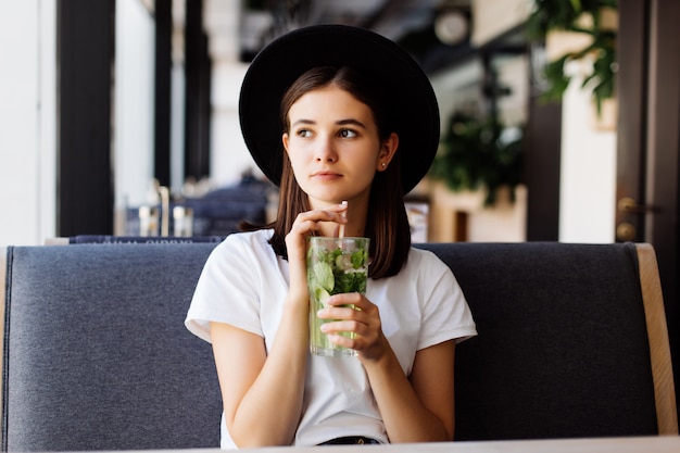 Hermosa joven beber limonada en café