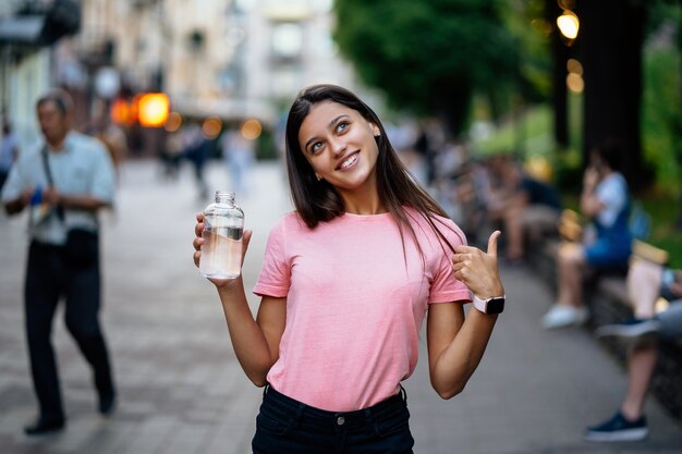 Hermosa joven con una botella de agua en una calle de la ciudad