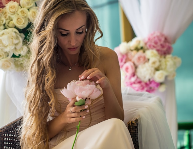 hermosa joven con cabello largo con flores reales en manos del suave misterio