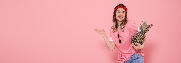 Foto gratuita hermosa joven en camiseta rosa, sonriendo con piña
