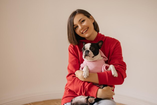 Hermosa joven caucásica sonríe a la cámara sosteniendo suavemente al perro sobre fondo blanco Concepto de amor animal