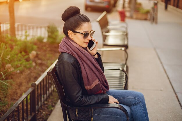 hermosa joven en una chaqueta de cuero y bufanda sentada en las calles de Chicago