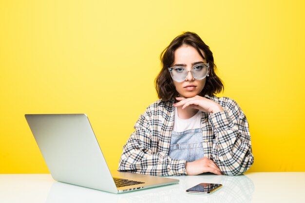 Hermosa joven concentrada trabajando en equipo portátil