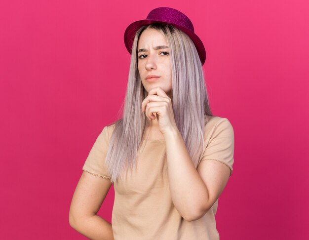 Hermosa joven confiada con sombrero de fiesta agarró la barbilla