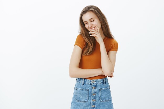 Hermosa joven coqueta ruborizarse y apartar la mirada coqueta, sonriendo feliz