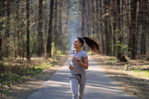 Hermosa joven corriendo en el parque verde en un día soleado de verano